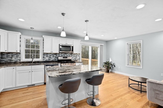 kitchen featuring sink, decorative light fixtures, white cabinets, and appliances with stainless steel finishes