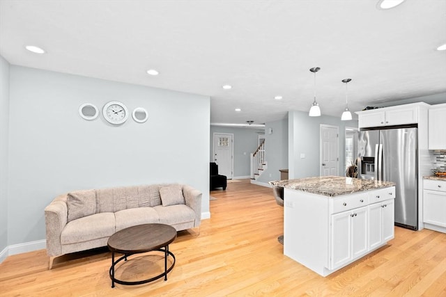 kitchen featuring hanging light fixtures, a kitchen island, white cabinets, and stainless steel fridge with ice dispenser