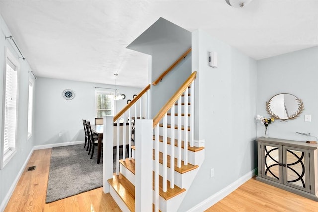 stairway featuring a notable chandelier and hardwood / wood-style flooring