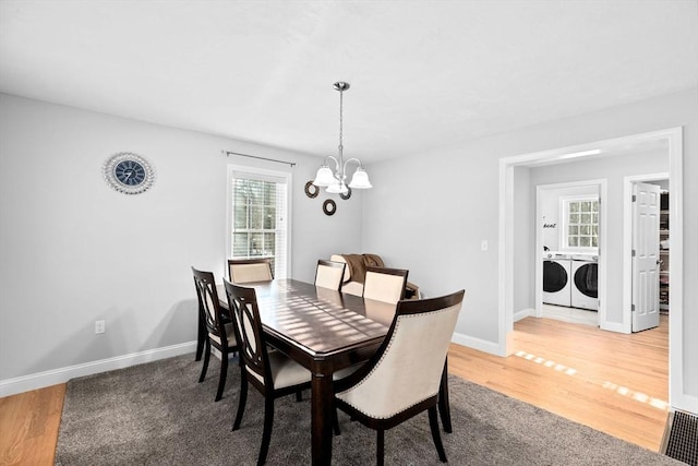 dining area with hardwood / wood-style flooring, washer and clothes dryer, and a notable chandelier