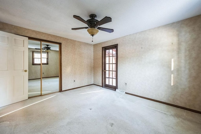 unfurnished bedroom with ceiling fan, a closet, and multiple windows