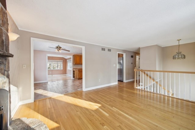 unfurnished room with a fireplace, ceiling fan, light hardwood / wood-style floors, and ornamental molding