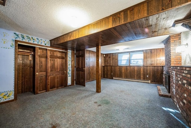 basement featuring wood walls, carpet, a fireplace, a baseboard heating unit, and a textured ceiling