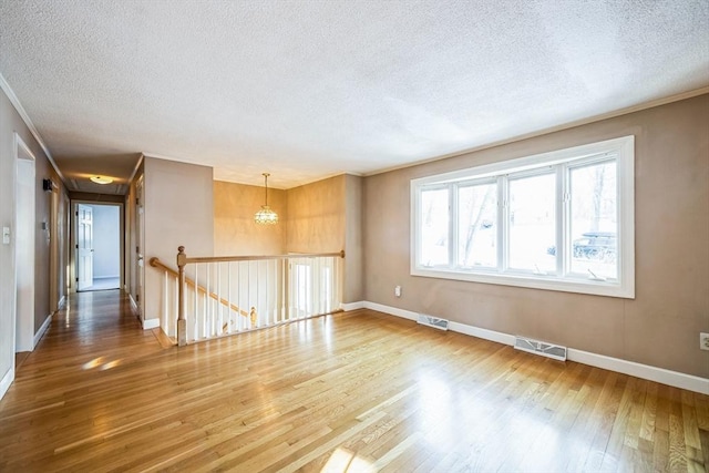 unfurnished room featuring a chandelier, hardwood / wood-style floors, and a textured ceiling