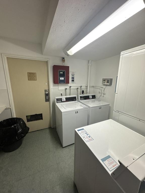 clothes washing area with washing machine and clothes dryer, electric panel, and a textured ceiling