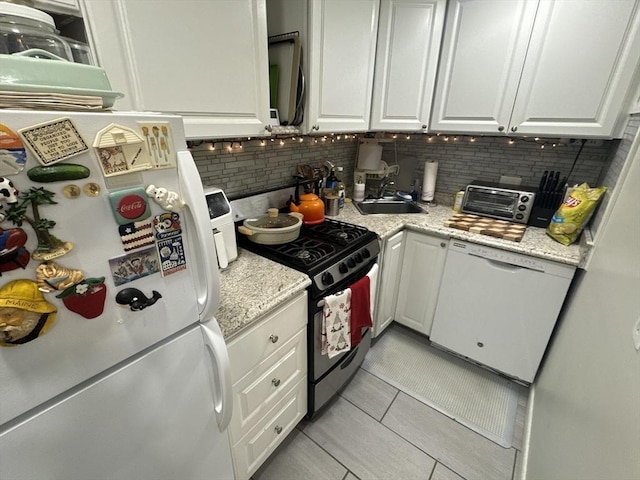 kitchen featuring sink, light tile patterned floors, backsplash, white appliances, and white cabinets