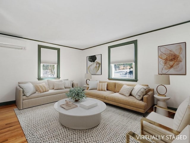 living room with an AC wall unit, light wood-style floors, crown molding, and baseboards
