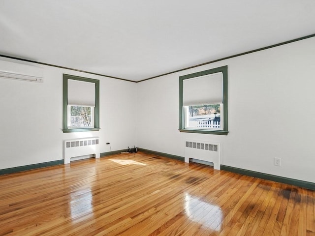 empty room featuring ornamental molding, radiator, a wall unit AC, and hardwood / wood-style flooring