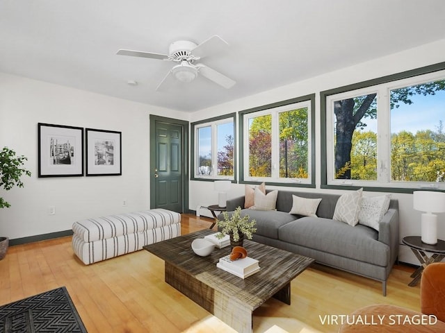 living room featuring baseboards, a ceiling fan, light wood finished floors, and a wealth of natural light