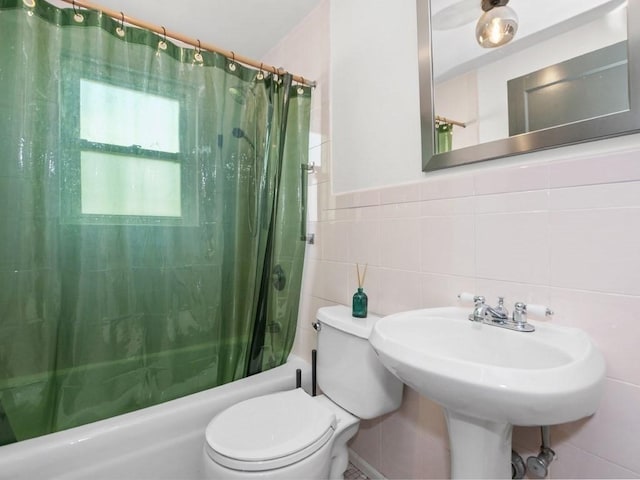 bathroom with a sink, tile walls, toilet, and shower / bath combination with curtain