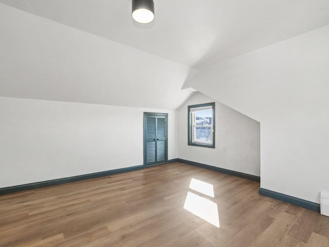 bonus room featuring baseboards, light wood-type flooring, and lofted ceiling