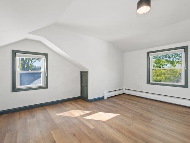 bonus room featuring baseboard heating, baseboards, wood finished floors, a baseboard radiator, and vaulted ceiling