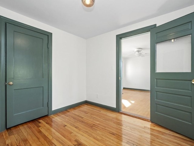 empty room featuring baseboards, a ceiling fan, and light wood finished floors
