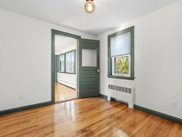 spare room with light wood-style floors, baseboards, radiator, and a baseboard heating unit