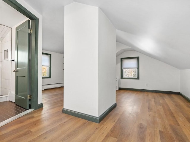 additional living space with a baseboard radiator, radiator, wood finished floors, and vaulted ceiling