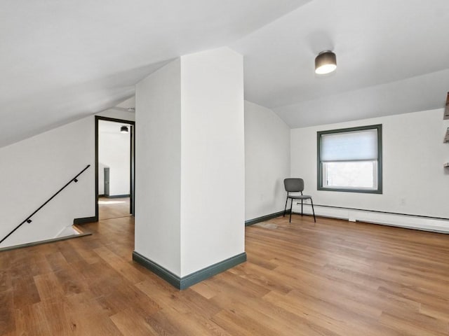 additional living space featuring light wood-style floors, baseboards, a baseboard heating unit, and lofted ceiling