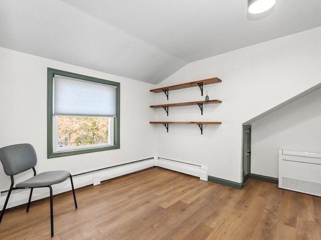 unfurnished room with baseboard heating, baseboards, vaulted ceiling, and wood finished floors