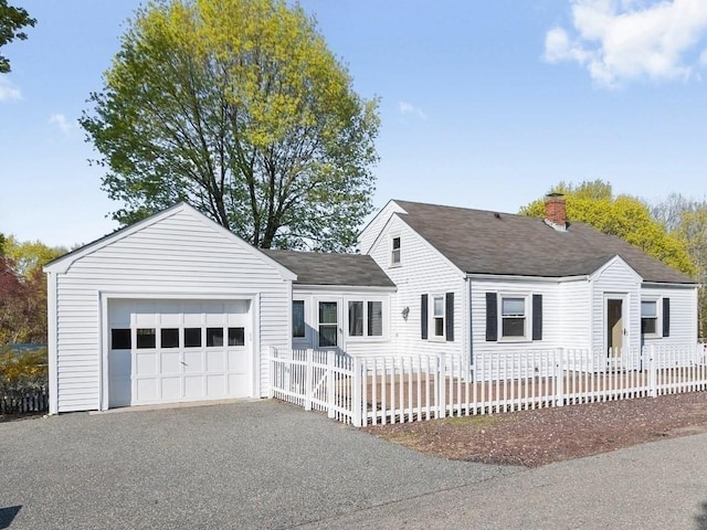 view of front of home with roof with shingles, an attached garage, a fenced front yard, a chimney, and driveway