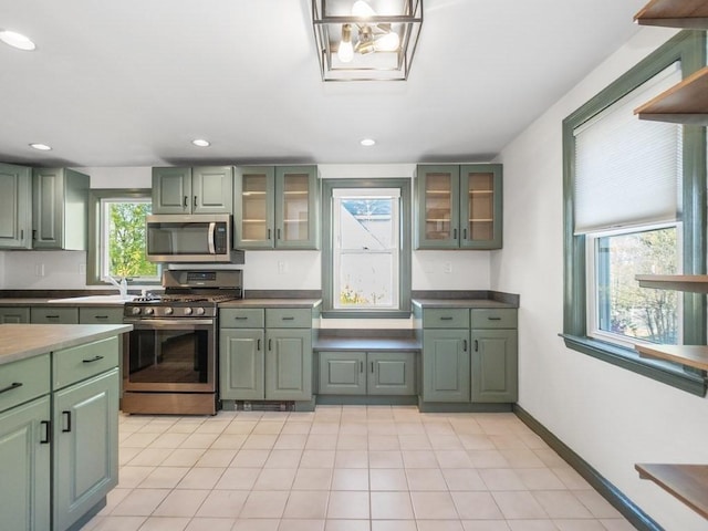 kitchen featuring glass insert cabinets, green cabinetry, stainless steel appliances, and recessed lighting