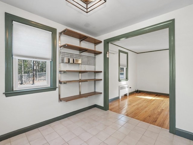 unfurnished room featuring light tile patterned flooring, baseboards, and radiator heating unit