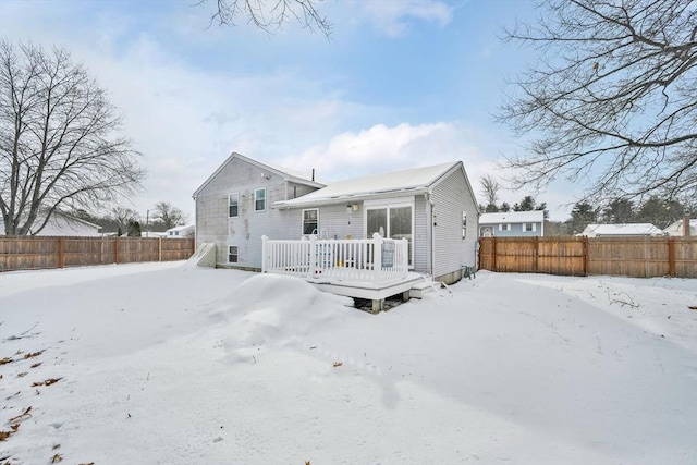 snow covered house featuring fence private yard and a deck