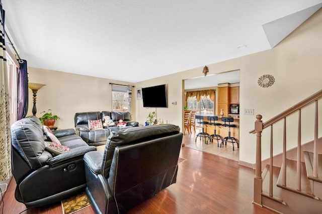 living area with a healthy amount of sunlight, stairway, and wood finished floors