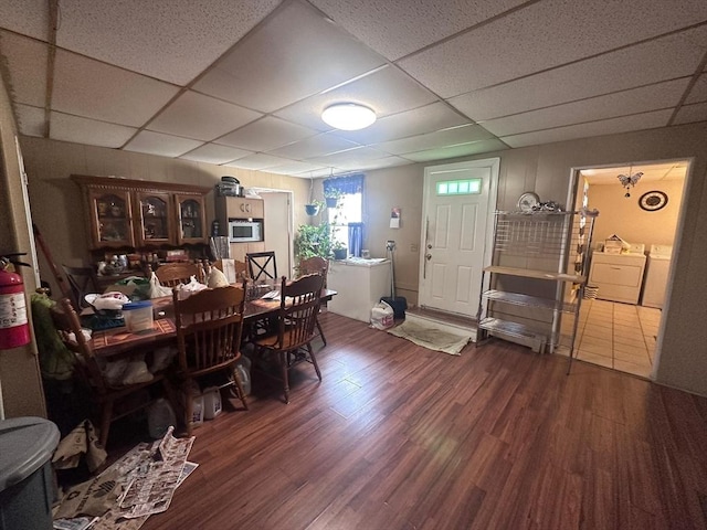 dining room with separate washer and dryer, wood finished floors, and a drop ceiling