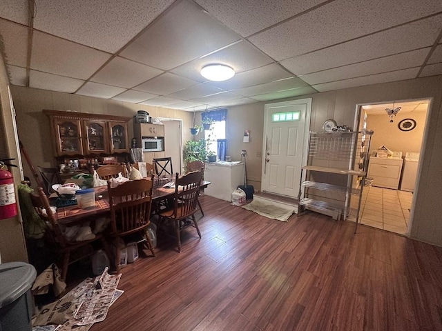 dining room with washing machine and dryer, wood finished floors, and a drop ceiling