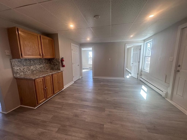 unfurnished dining area featuring a baseboard heating unit, baseboards, and dark wood-type flooring