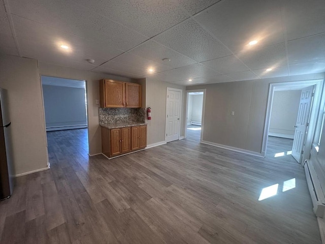 kitchen with a baseboard heating unit, dark wood-style floors, tasteful backsplash, baseboards, and brown cabinetry