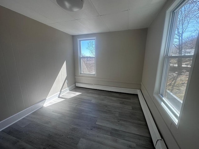 unfurnished room with baseboard heating, baseboards, and dark wood-style flooring