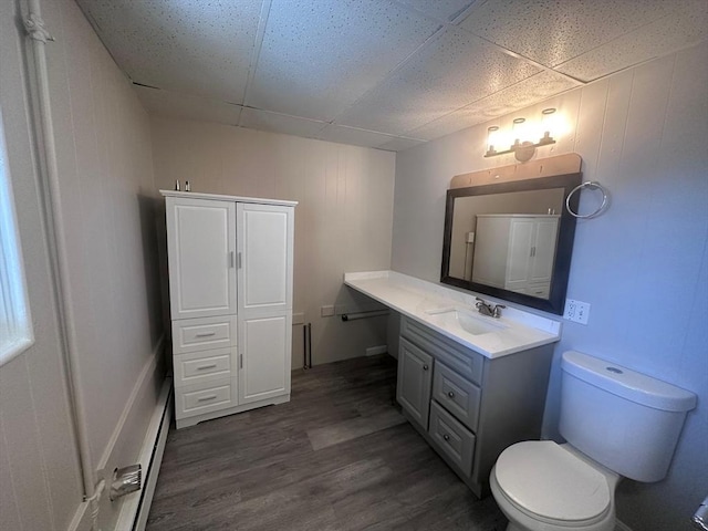 bathroom featuring wood finished floors, toilet, vanity, and a drop ceiling