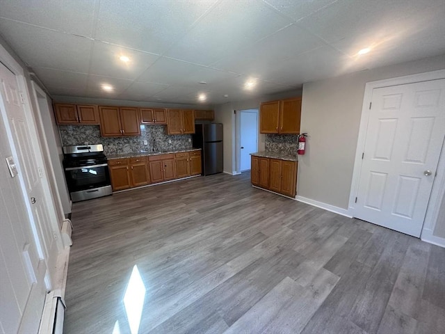 kitchen featuring wood finished floors, brown cabinets, decorative backsplash, electric range, and freestanding refrigerator