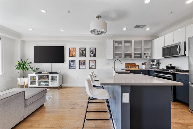kitchen with visible vents, a peninsula, stainless steel appliances, light wood-type flooring, and a breakfast bar area