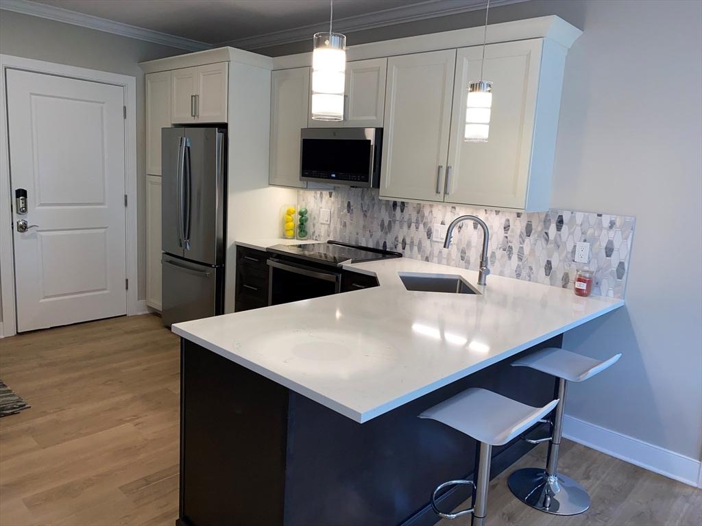 21 Totman St Unit 309, Quincy, MA 02169 - kitchen with appliances with stainless steel finishes, light countertops, light wood-style floors, and crown molding
