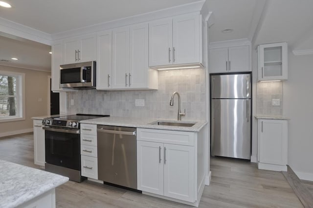 kitchen featuring stainless steel appliances, backsplash, a sink, and white cabinets