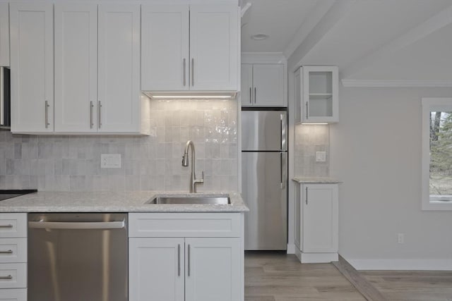 kitchen with stainless steel appliances, tasteful backsplash, a sink, and white cabinetry