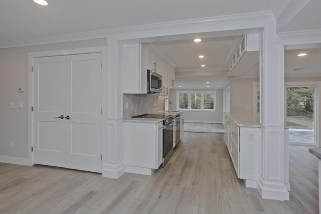 kitchen featuring electric stove, stainless steel microwave, white cabinetry, and crown molding