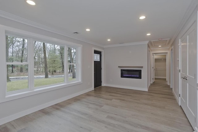 unfurnished living room featuring ornamental molding, light wood-type flooring, visible vents, and baseboards