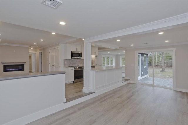 unfurnished living room featuring light wood-type flooring, visible vents, crown molding, and a glass covered fireplace