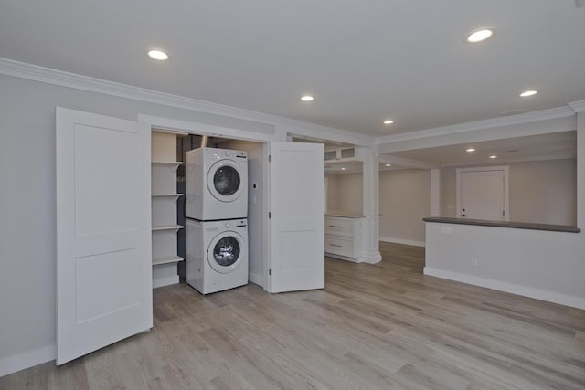 laundry room featuring laundry area, light wood-style flooring, ornamental molding, and stacked washer / drying machine