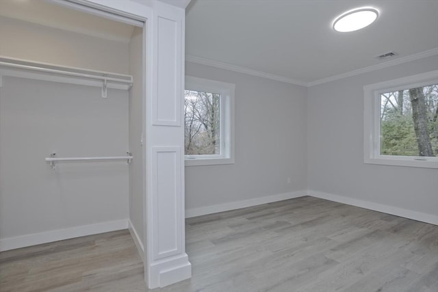 unfurnished bedroom with baseboards, visible vents, wood finished floors, crown molding, and a closet