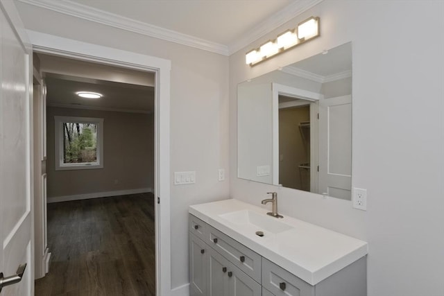 bathroom with ornamental molding, wood finished floors, vanity, and baseboards