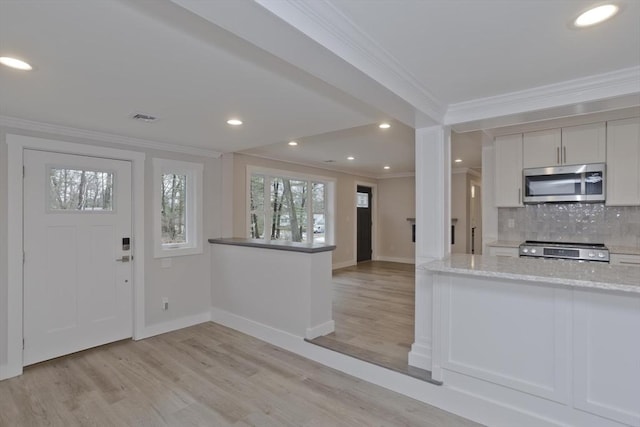 entryway featuring baseboards, light wood-style flooring, visible vents, and crown molding