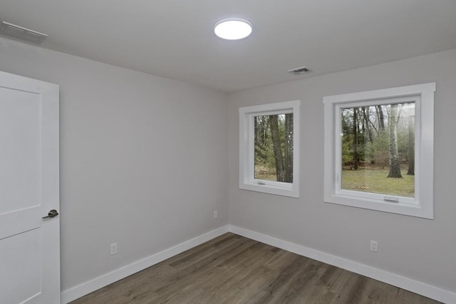 spare room with visible vents, baseboards, and dark wood finished floors