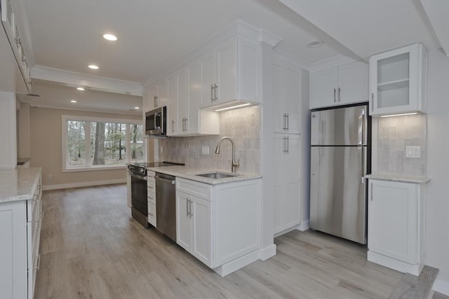 kitchen with stainless steel appliances, white cabinetry, a sink, and backsplash