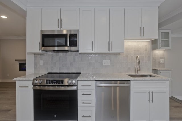 kitchen featuring decorative backsplash, appliances with stainless steel finishes, ornamental molding, wood finished floors, and a sink