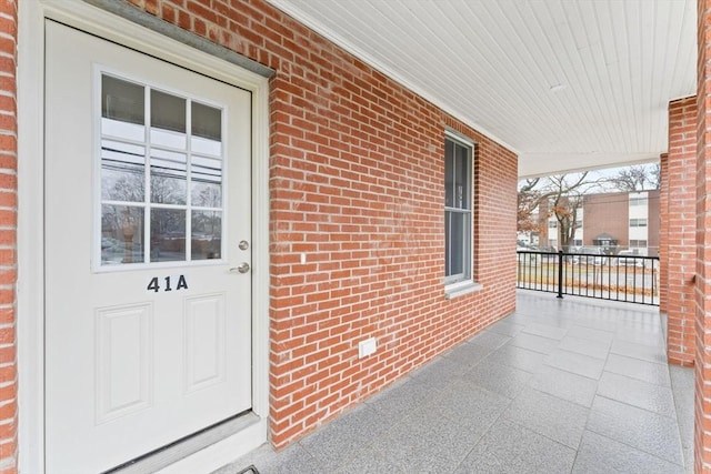 doorway to property with covered porch and brick siding