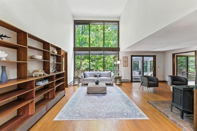 26 Ashfield Ln, South Hadley, MA 01075 - living area with a towering ceiling, a wood stove, a baseboard heating unit, and light wood-style floors