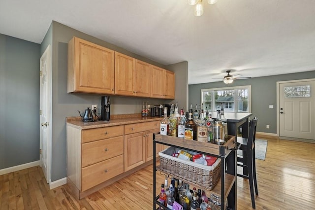 kitchen with light brown cabinets, baseboards, light countertops, light wood-style floors, and a ceiling fan